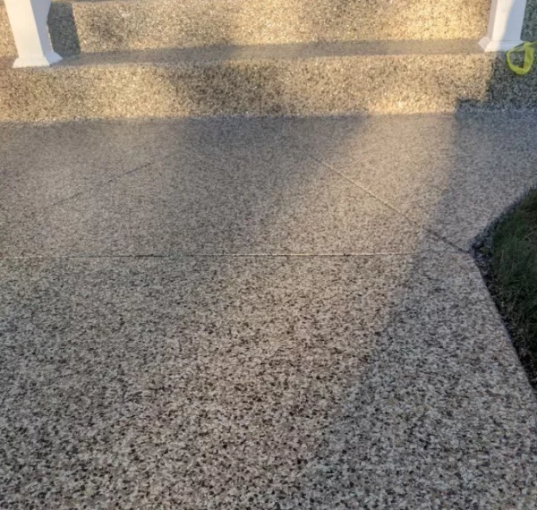 This image shows a shadow of a person with arms akimbo cast upon a textured ground, with sunlight creating contrast, adjacent to stairs and grass.