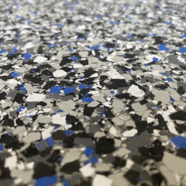 The image depicts a close-up of a speckled surface with a mixture of black, white, and blue fragments, potentially a type of terrazzo flooring or countertop.
