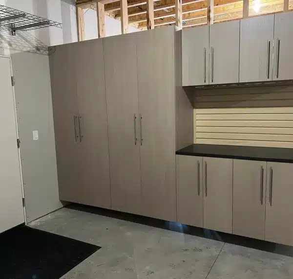 A photo of a gray storage cabinet setup in a room with unfinished walls, a concrete floor, and a dark mat by the door.